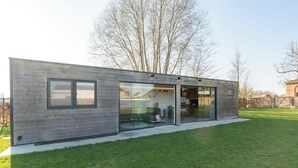 Een modern, gelijkvloers gebouw met grote glasramen, een plat dak en een gazon.