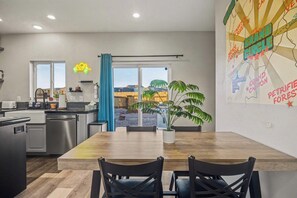 A modern kitchen with a dining area, a large window, and a map on the wall. - Kanab Desert Escape | Hot Tub, Views & Stargazing (Kanab)