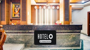 A hotel reception desk with a sign indicating company service, a decorative altar, and a modern ceiling design. - Super Hotel O Gurudwara (Visakhapatnam)