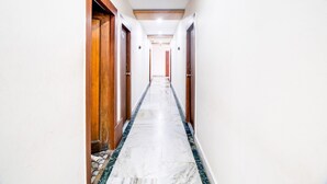 A long, narrow hallway with wooden doors on both sides, leading to a room at the end. - Super Hotel O Gurudwara (Visakhapatnam)