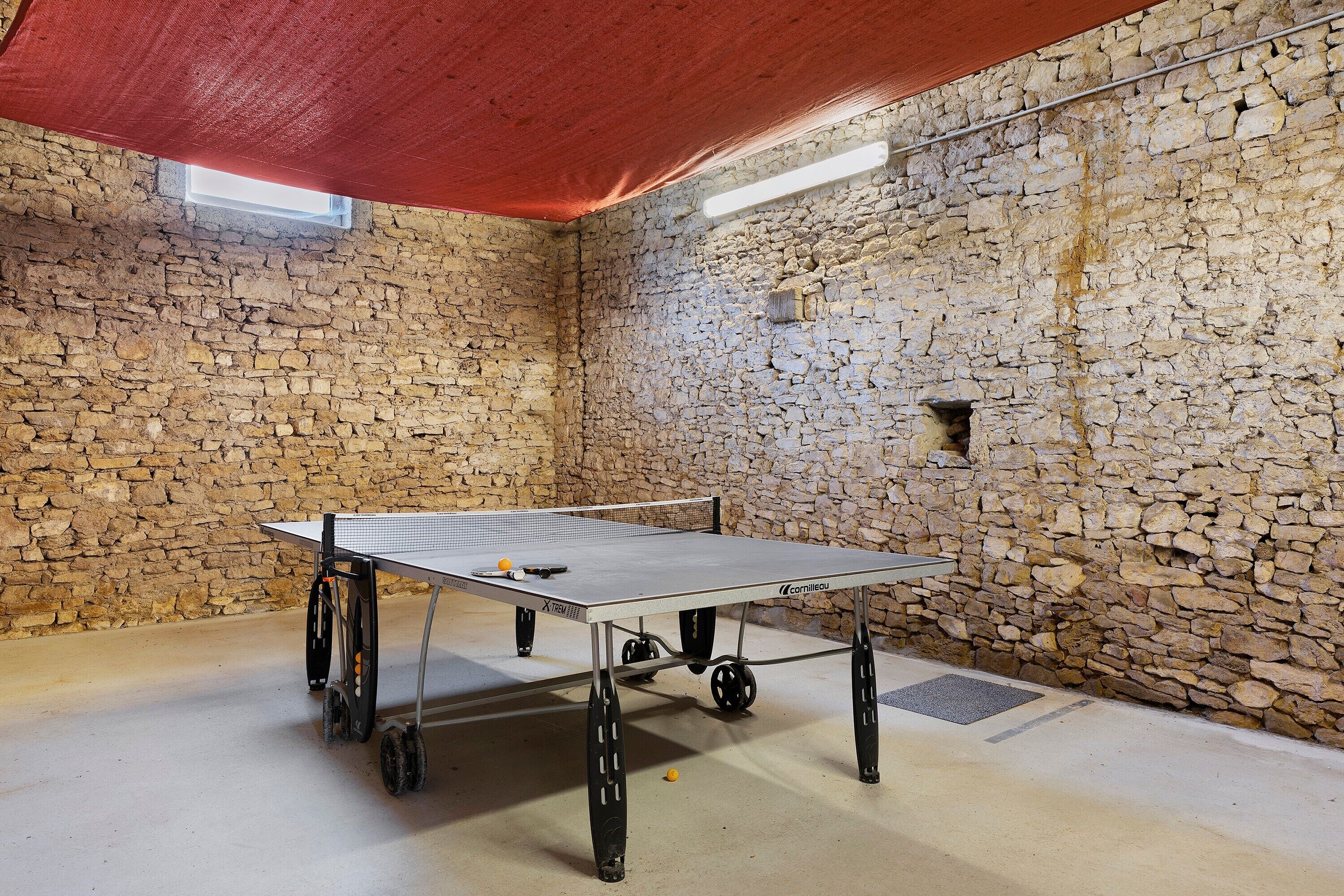 Ein Tischtennistisch in einem Raum mit Steinwänden und einer roten Decke.