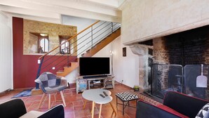 Ein Wohnzimmer mit Fernseher, Sitzgelegenheiten, Kamin und einer Treppe.