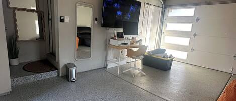 A spacious room with a large TV, a desk, and a chair.