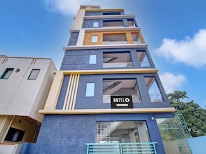 Un hôtel à plusieurs étages, doté d’un design moderne, et dont la façade est ornée d’une grande enseigne indiquant le mot « HÔTEL ».