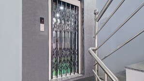 A modern elevator with a metallic, geometric design and a glass panel.