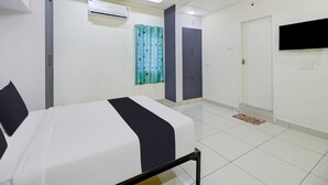 A bedroom with a bed, an air conditioning unit, a ceiling fan, a TV mounted on the wall, and a door.