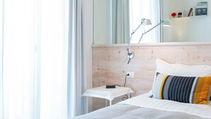 A modern hotel room with a bed, bedside table, lamp, and a view of the outdoors. - Hotiday Porto Cesareo Laguna (Porto Cesareo)