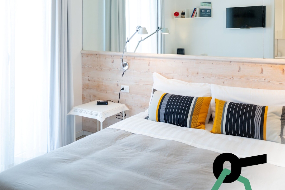 Ein Hotelzimmer mit einem Bett, einem Schreibtisch, einer Lampe, einem Fernseher und einem Spiegel.