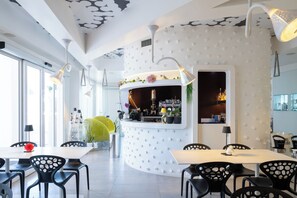 A modern interior with a curved reception desk, black chairs, and a white ceiling with a unique pattern. - Hotiday Porto Cesareo Laguna (Porto Cesareo)
