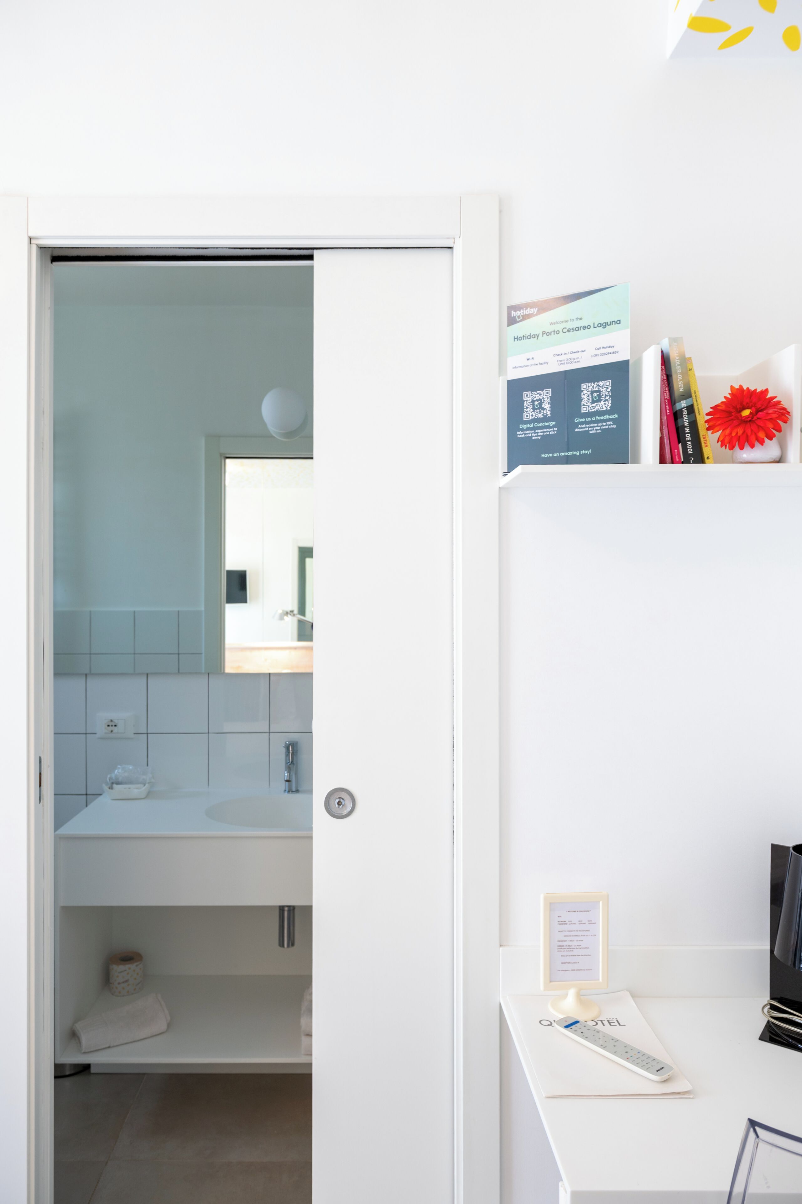 Een hotelbadkamer met een witte wastafel, een spiegel en een handdoekhouder.