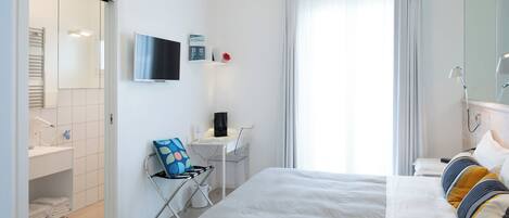 Hotellihuone, jossa on sänky, työpöytä, tuoli, televisio ja kylpyhuone.