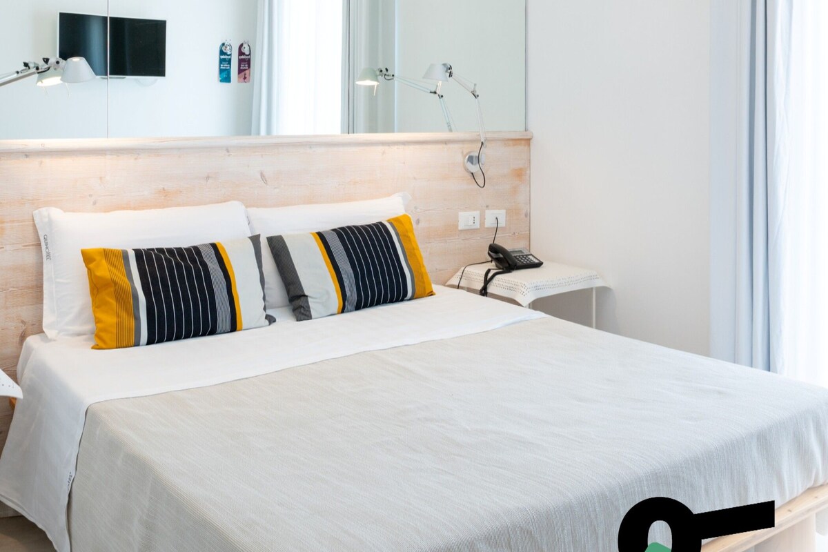 Quarto moderno com uma cama grande, uma mesa de cabeceira, um espelho e um teto com padrão de folhas.