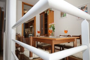 A dining area with a wooden table and chairs, two glasses of orange beverage, and a vase with flowers. - La Dolce Vita - Lake Como - Tremezzo - near the lake (Tremezzo)