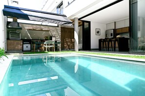 A swimming pool with a covered outdoor seating area, a kitchen, and a bar. - Casa Marina Piccola (São Sebastião)