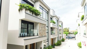 Un edificio moderno con balcones, ventanas amplias y plantas en macetas.