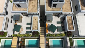 Un edificio moderno con varios balcones, mobiliario exterior y piscinas.