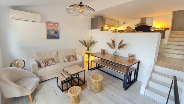 Un salon moderne avec un canapé, une table basse et une table à manger. Un escalier mène à un niveau supérieur.