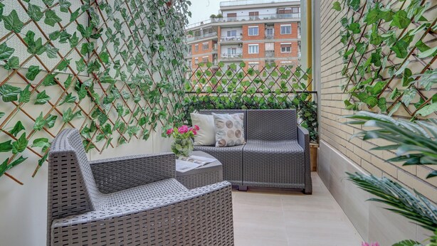 A balcony with wicker furniture, a small table, and a vase with flowers. - SAN GIOVANNI Appia Park - Stylish apartment with balcony - Metro A - 10 min City Center (Rome)