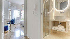 Un bagno moderno con un lavandino ampio, cabina doccia in vetro e specchio con illuminazione circolare.