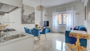 A modern kitchen with a sink, dining area with chairs, a table, a TV, and a window with curtains. - SAN GIOVANNI Appia Park - Stylish apartment with balcony - Metro A - 10 min City Center (Rome)