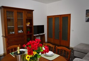 Ein Essbereich mit einer Holzkabine, einem Fernseher und einem Tisch, gedeckt mit einem Blumenstrauß und einer Champagnerflasche.