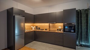 Eine moderne Küche mit dunklen Schränken, einem Edelstahlkühlschrank, einem eingebauten Ofen und einer Holz Arbeitsplatte.