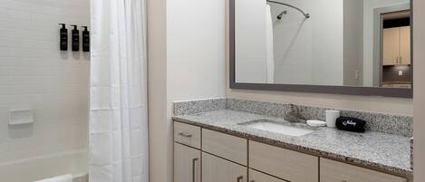 A bathroom with a shower, a sink, and a mirror.