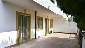 Un edificio con patio piastrellato, porte a cornice gialla e facciata bianca.