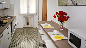 Una cucina moderna con zona pranzo, un termosifone, un forno a microonde e un quadro raffigurante una spiaggia.