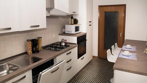 A modern kitchen with a stainless steel sink, a microwave, a gas stove, and a dishwasher. - Cattel A05 with Private Terrace and Air Conditioning (Lido di Jesolo)