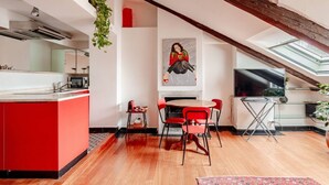A modern kitchen with a red island, a dining area with red chairs, a fireplace, and a large TV. - Panoramic apartment with a view of the Po River (Torino)