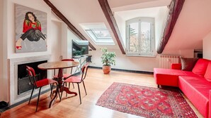 A loft-style room with a dining area, red sofa, and a large window. - Panoramic apartment with a view of the Po River (Torino)