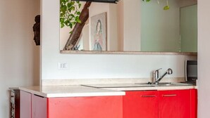 A kitchen with a red cabinet, a sink, and a microwave. - Panoramic apartment with a view of the Po River (Torino)