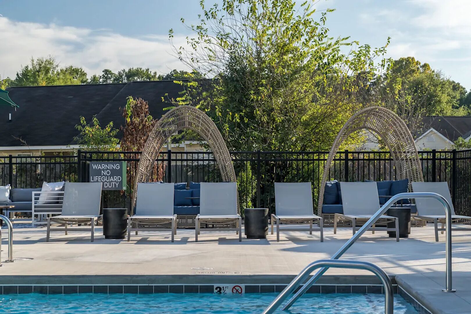 A poolside area with lounge chairs, a lifeguard duty sign, and a pool with a no diving sign.