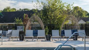 A poolside area with lounge chairs, a lifeguard duty sign, and a pool with a no diving sign.