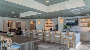 A modern kitchen with a central island, pendant lighting, and a dining area with wooden chairs. - Landing Apartments Near Woodcrest (Raleigh)