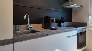 A modern kitchen with a stainless steel range hood, a coffee machine, and a built-in oven. - Modern apartment for 2-4 guests with balcony (Bruttig-Fankel)