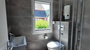 A bathroom with a toilet, a shower, a window, and a towel rack. - Modern apartment for 2-4 guests with balcony (Bruttig-Fankel)