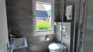 A bathroom with a toilet, a shower, a window, and a towel rack. - Modern apartment for 2-4 guests with balcony (Bruttig-Fankel)