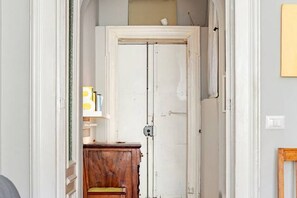 Ein schmaler Flur mit einer weißen Tür, einem Holzschrank und einem kleinen Tisch mit einem Stuhl.