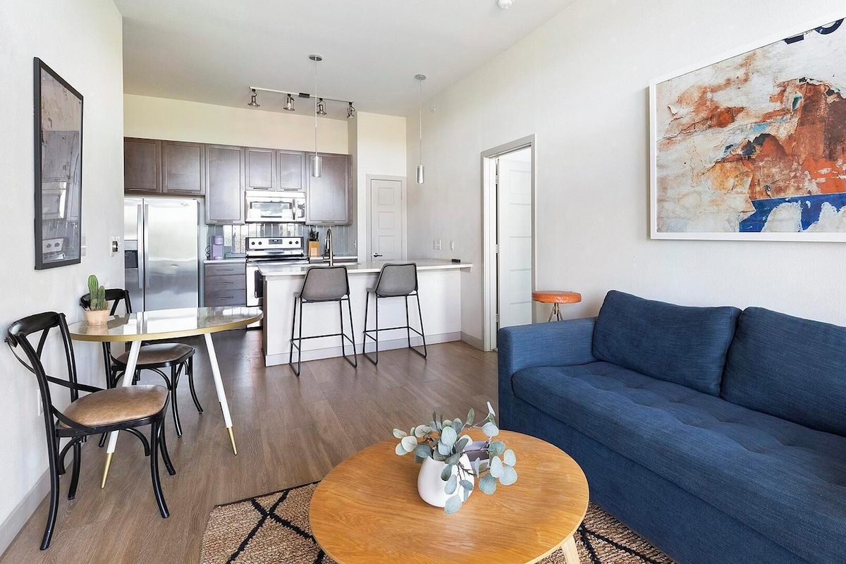 A modern apartment with a living room, dining area, and kitchen.