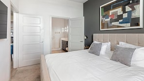 A bedroom with a large bed, a nightstand, a wall-mounted painting, and a closet with a sliding door. - Landing Apartments Near Southtown (San Antonio)