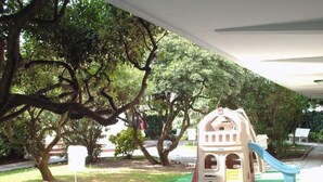Una caseta de jocs infantil amb tobogan, envoltada d'arbres.