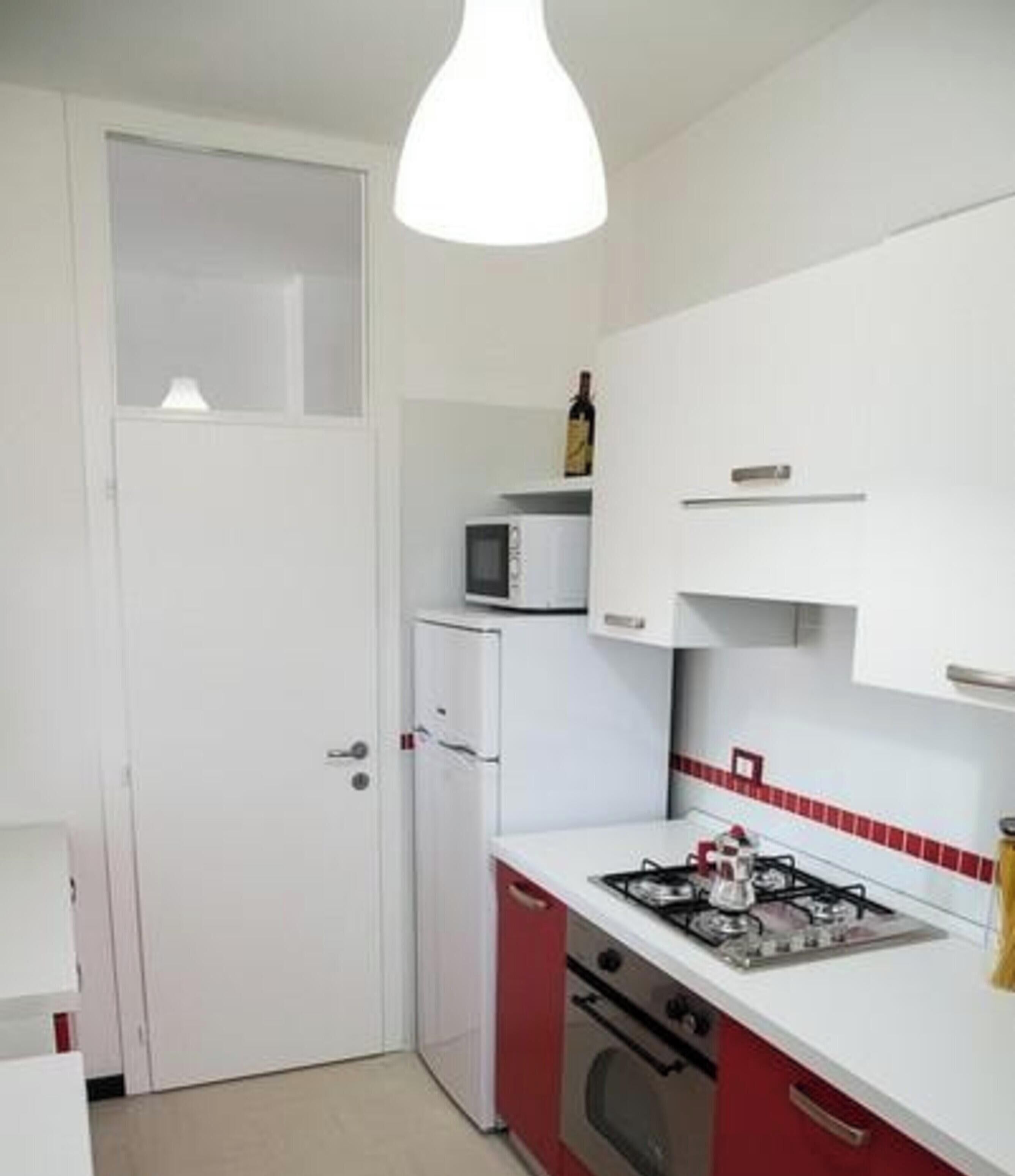 Een kleine keuken met een magnetron, een gasfornuis en een koelkast.