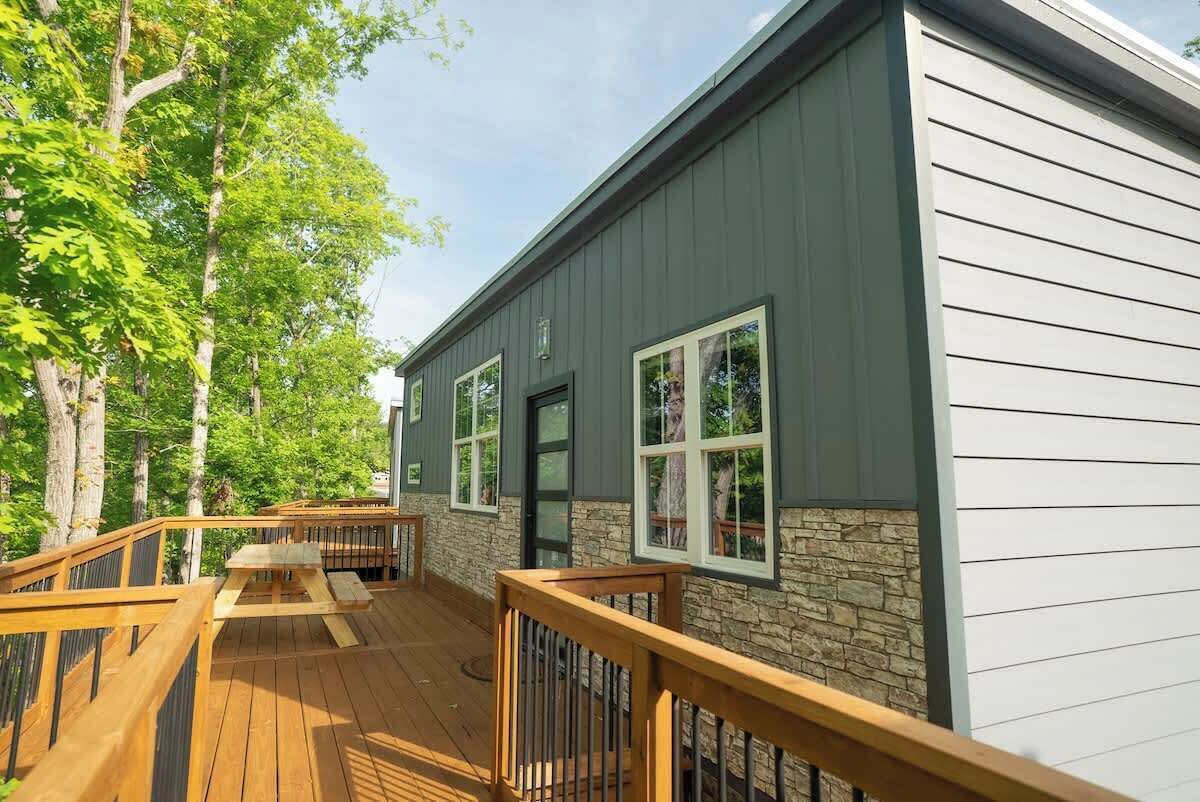A building with a deck, stone wall, and large windows.