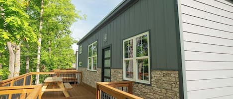 A building with a deck, stone wall, and large windows.
