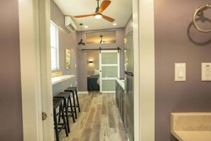 A narrow hallway leading to a kitchen with a ceiling fan, a window, and a door. - Greystone (Anderson)