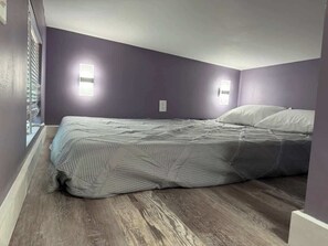 A bedroom with a bed, two wall-mounted lights, and a window. - Greystone (Anderson)