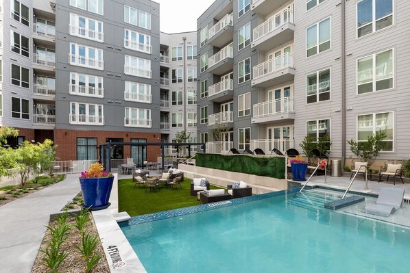 A modern apartment building with a rooftop pool area, outdoor seating, and a well-maintained garden. - Landing Apartments Fort Worth Near Historic Southside (Fort Worth)
