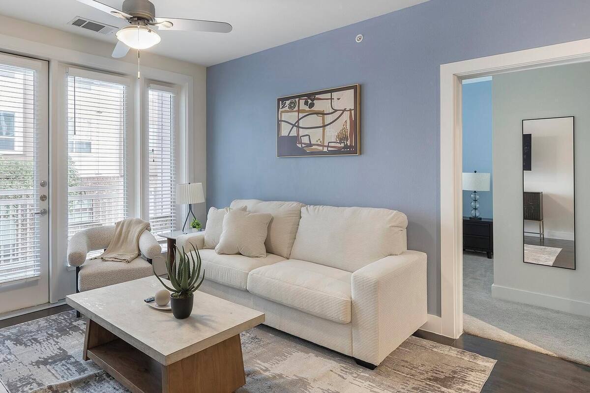 A living room with a beige sofa, a coffee table, and a ceiling fan.